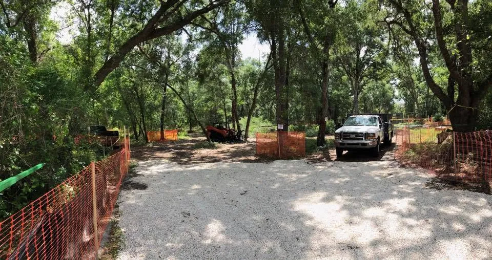 Access drive with safety fencing, truck and skid steer on a tree job near DeLand, FL