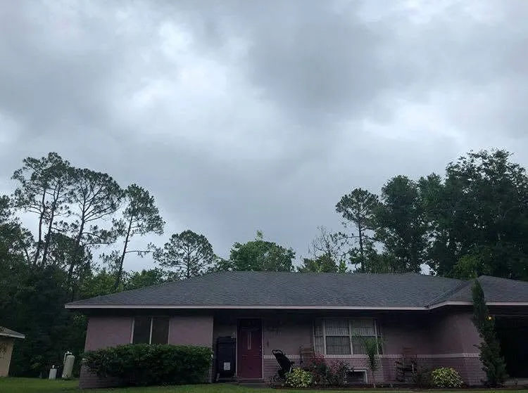 Tall pines looming over a DeLand, FL home under a dark storm sky